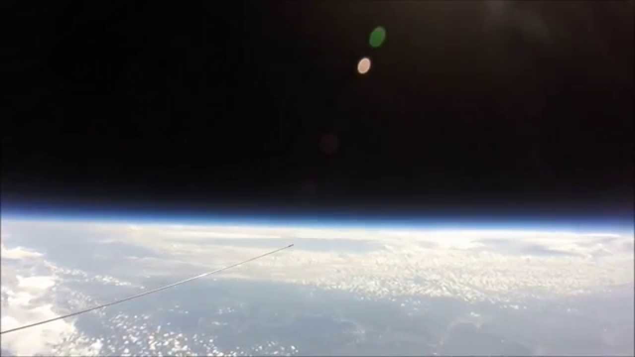 High-altitude balloon footage showing a flat horizon with the balloon tether visible in frame.